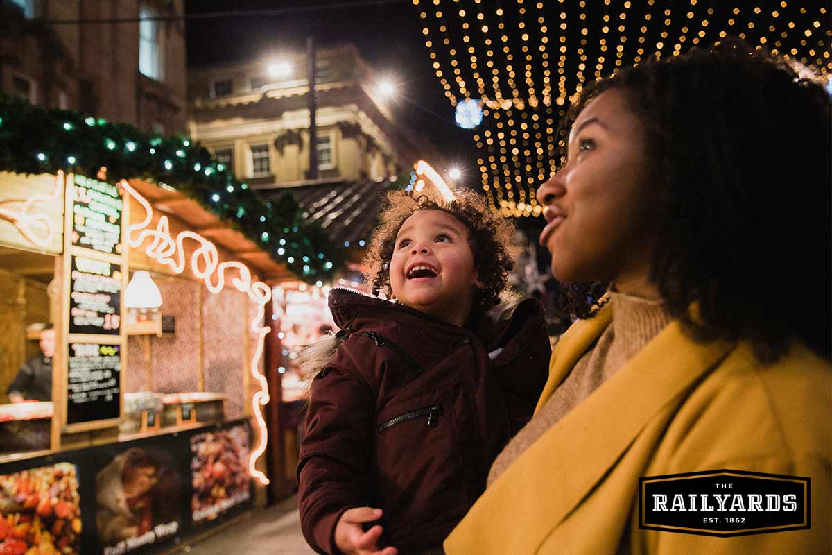 A woman holding her child looking up at the holiday lights. Discover 9 Sacramento holiday events.