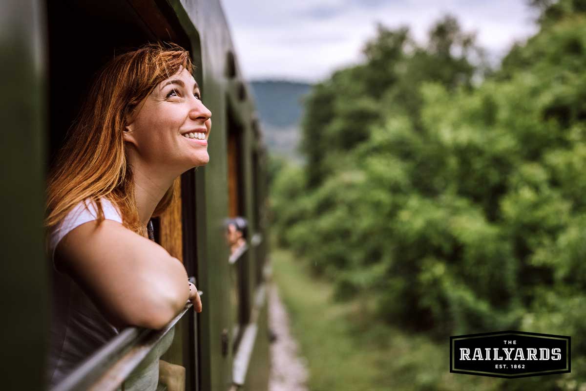Young woman smiling looking out of train window on a scenic trip. Find out where the Sac Valley Station will take you.